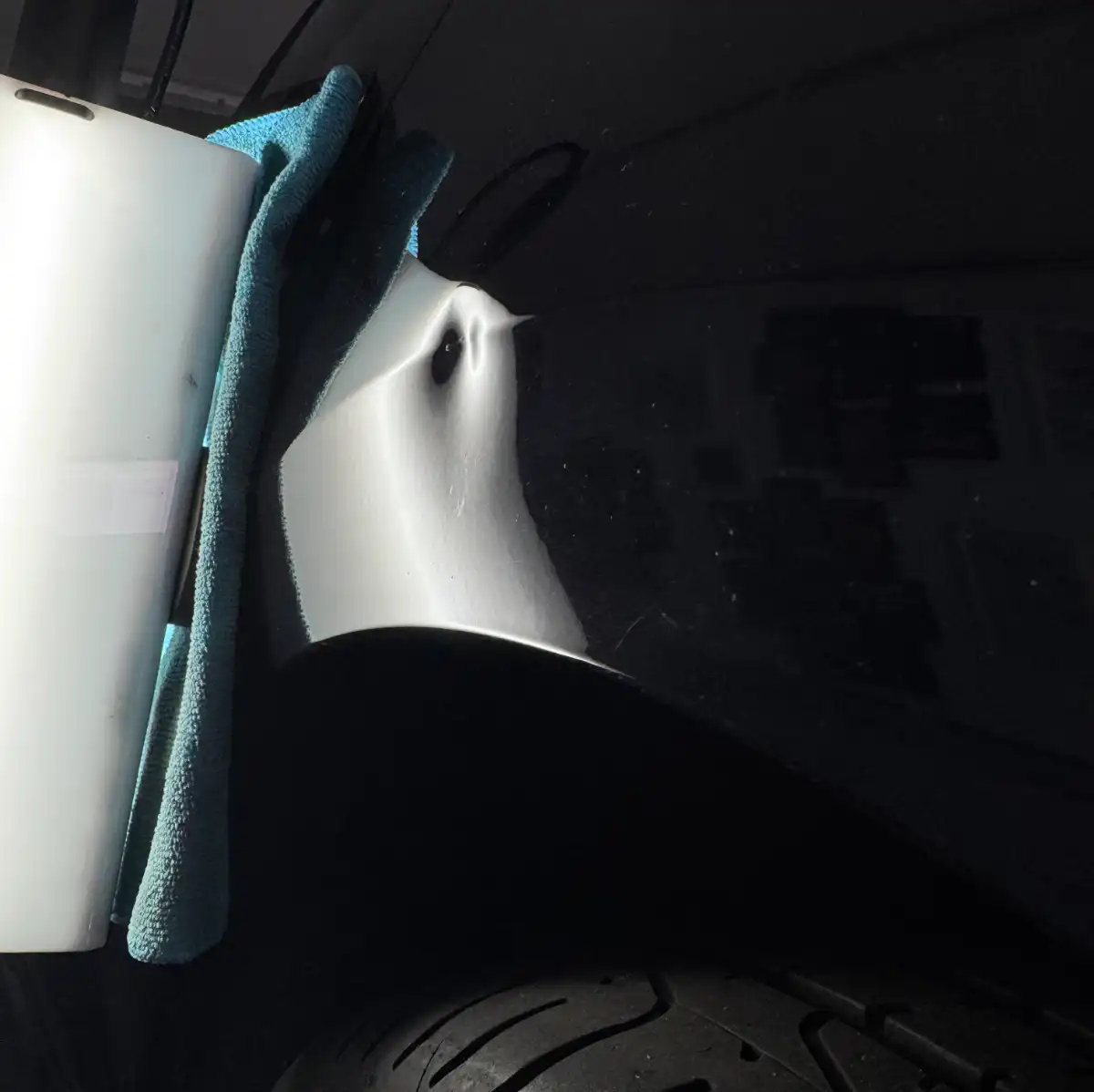 Autodelle am Kotflügel, Reflektoren und Tuch sichtbar.