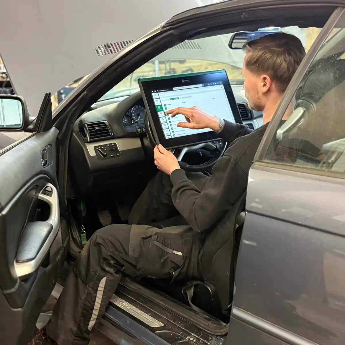 Mechaniker nutzt Diagnosegerät im Auto.