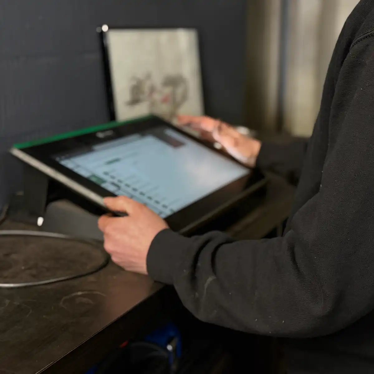 Person bedient großen Touchscreen-Monitor in Werkstatt.