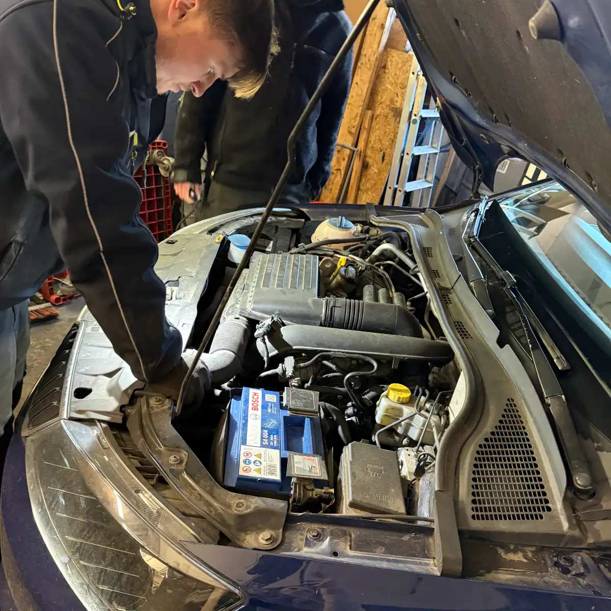 Mechaniker arbeitet am Motor eines Autos in Werkstatt.