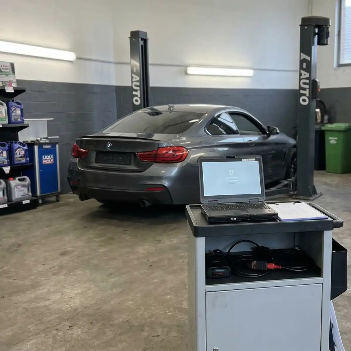 Graues Auto in einer Werkstatt mit Laptop.